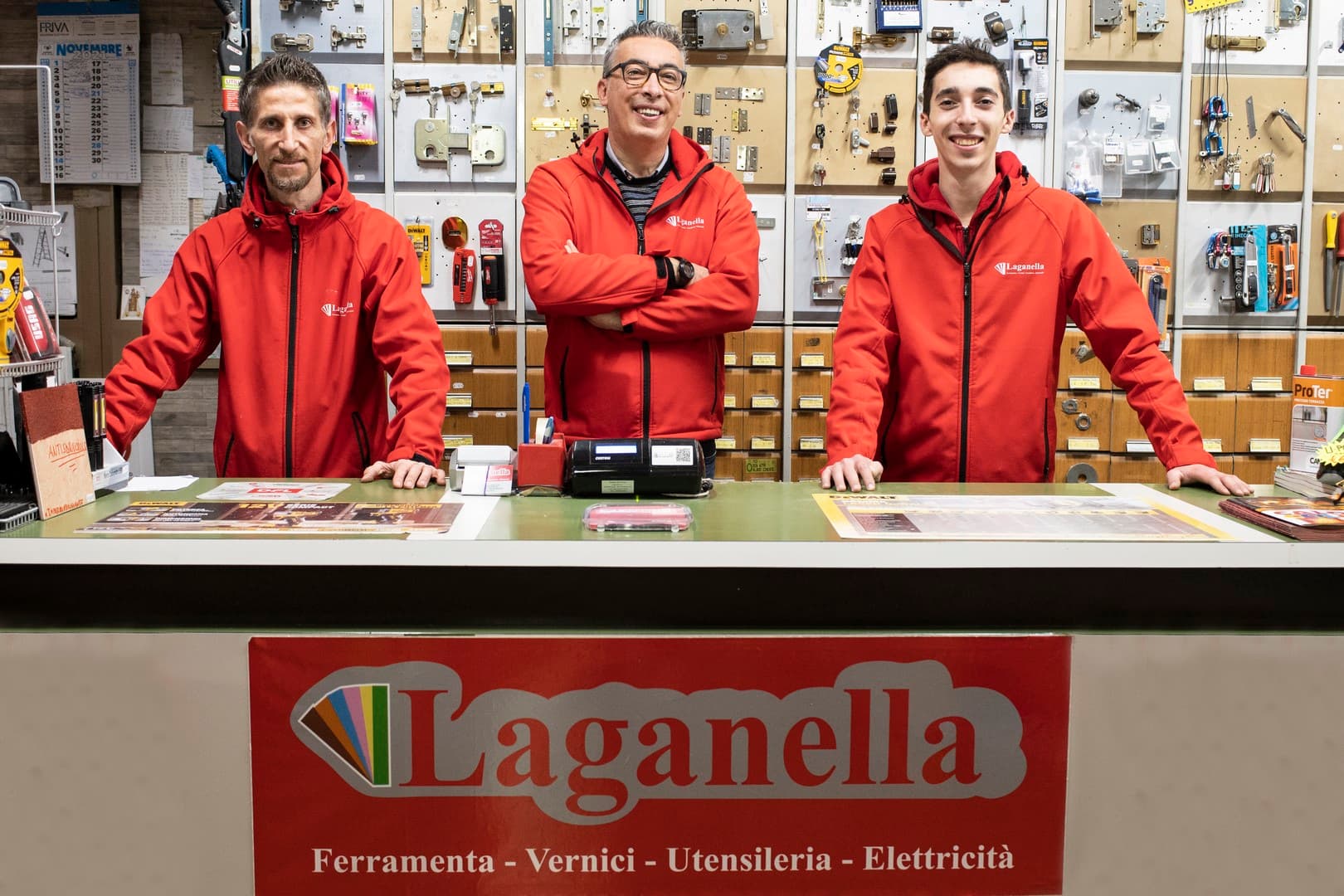 Tre persone dello staff Laganella, in giacca rossa, dietro il banco del negozio